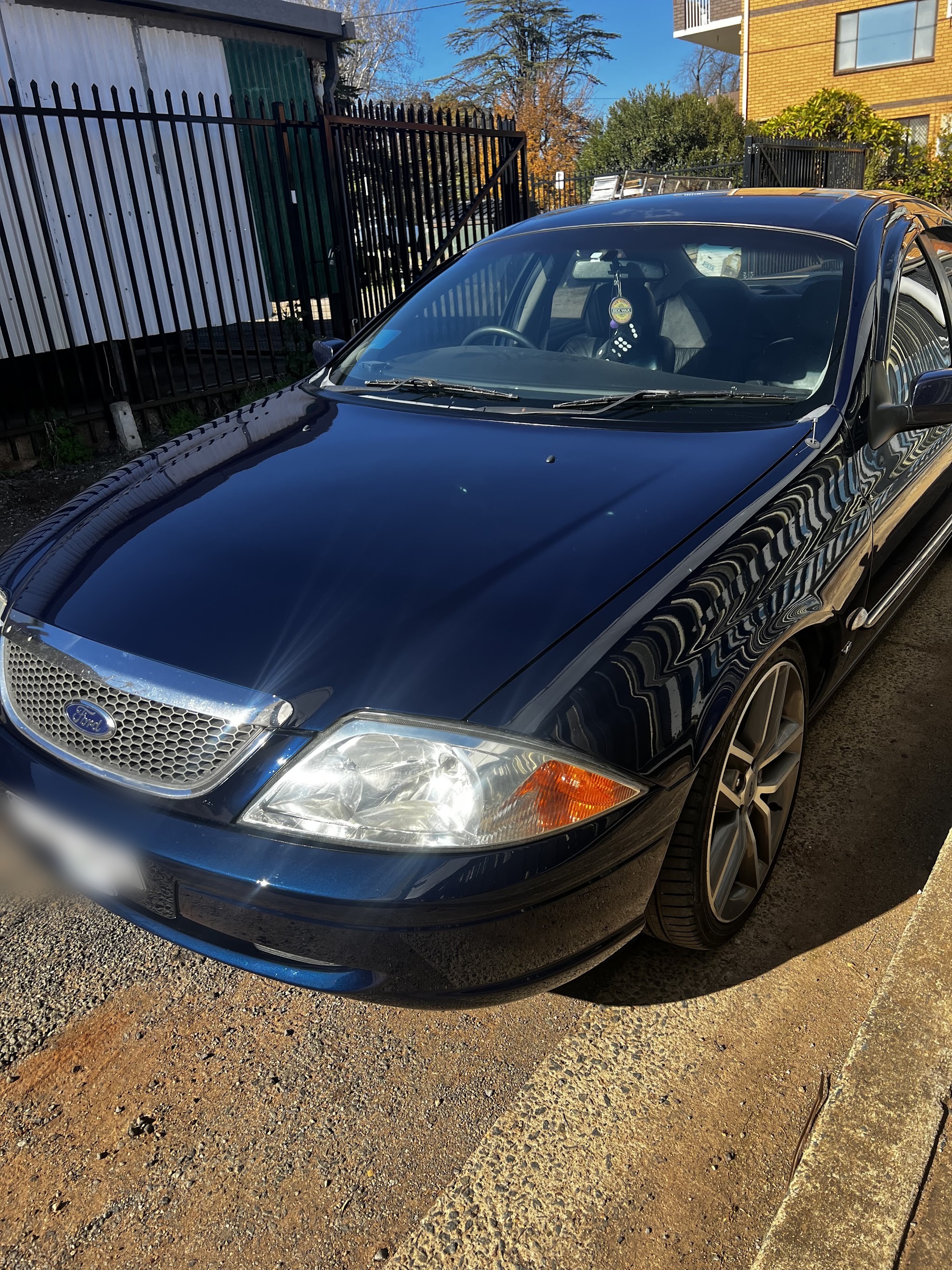 Dark blue Ford Falcon in bright sun, the panel work clean along the whole flank